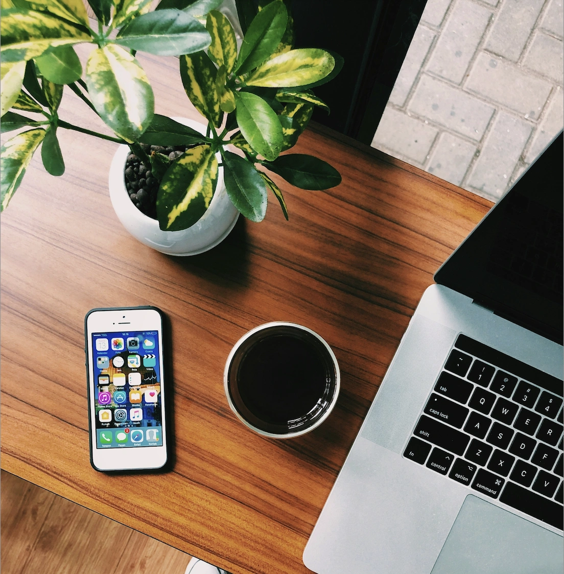 Bureau créatif Norvio Studio : smartphone, plante, café et laptop en flat-lay